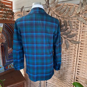 Puede incluir: Camisa de cuadros de manga larga en tonos turquesa, azul y marino. La camisa tiene un cuello cl&aacute;sico y pu&ntilde;os abotonados. El estampado de cuadros es un dise&ntilde;o tradicional.