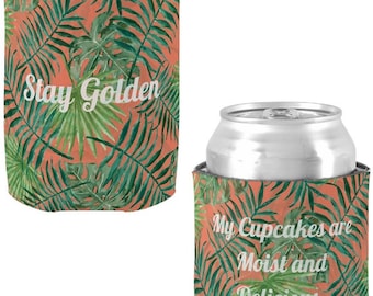 Peut inclure: Deux refroidisseurs de canettes avec un motif de feuilles tropicales. Un refroidisseur dit "Stay Golden" et l'autre dit "My Cupcakes are Moist and Delicious. Men Love My Cupcakes."