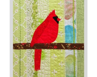 May include: Red cardinal collage art quilt with a green, white, and blue background. The quilt is 10 inches by 12 inches and is framed to 8 inches by 10 inches. *As published in Art Quilting Studio magazine Summer 2020*