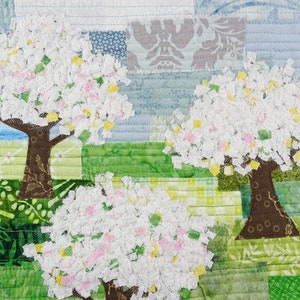 May include: A quilt depicting three trees with white, pink, and yellow blossoms against a blue and green background. The trees are made of fabric scraps and are sewn together to create a patchwork effect.