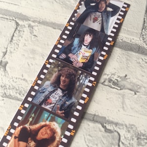 May include: A black and white film strip with four photos of a man with long curly hair. The man is wearing a denim jacket and a t-shirt with a graphic of a bull. The photos are in a vertical format and are separated by black film strips.
