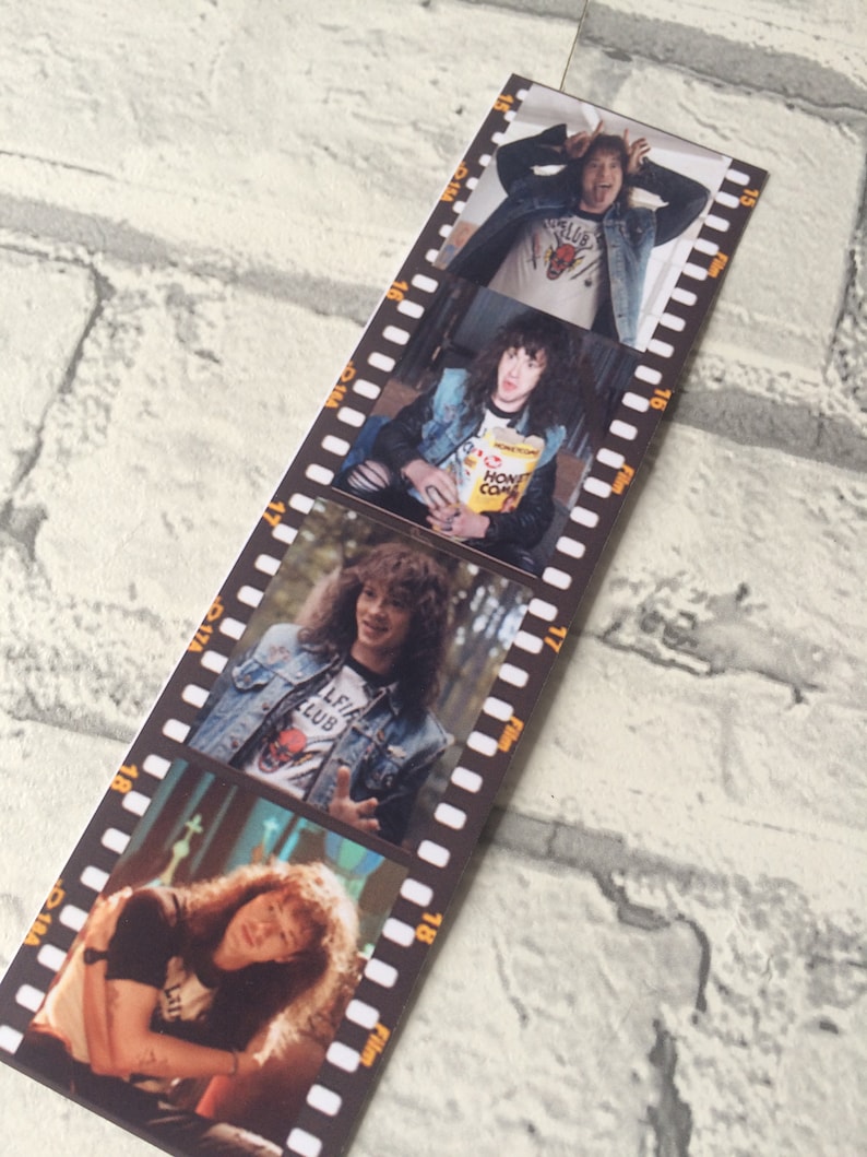May include: A black and white film strip with four photos of a man with long curly hair. The man is wearing a denim jacket and a t-shirt with a graphic of a bull. The photos are in a vertical format and are separated by black film strips.