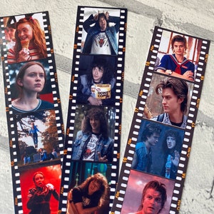 May include: A set of 3 film strip bookmarks featuring characters from the Netflix series Stranger Things. The bookmarks feature images of Eleven, Dustin, Mike, Lucas, and Steve.