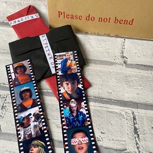 May include: Two black and white film strip bookmarks featuring characters from the show Stranger Things. The bookmarks have images of Eleven, Mike, Dustin, and Lucas.