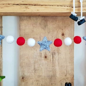 May include: A festive garland with red, white, and gray felt balls and stars. The garland is strung on white thread and is perfect for decorating for the holidays.