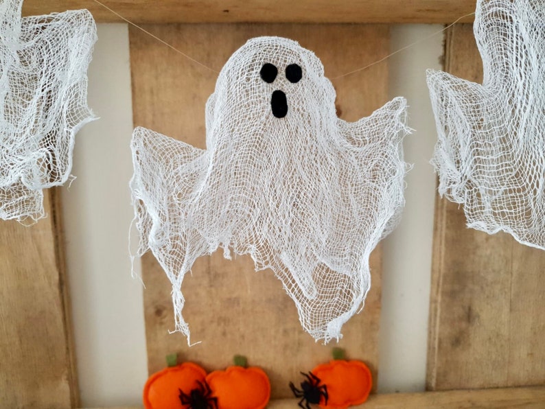 Peut inclure: Un fant&ocirc;me blanc en gaze avec des yeux noirs et une bouche suspendu &agrave; une ficelle. Le fant&ocirc;me est suspendu devant un fond en bois.