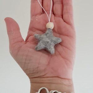 May include: A gray felt star ornament with a wooden bead and white string for hanging.