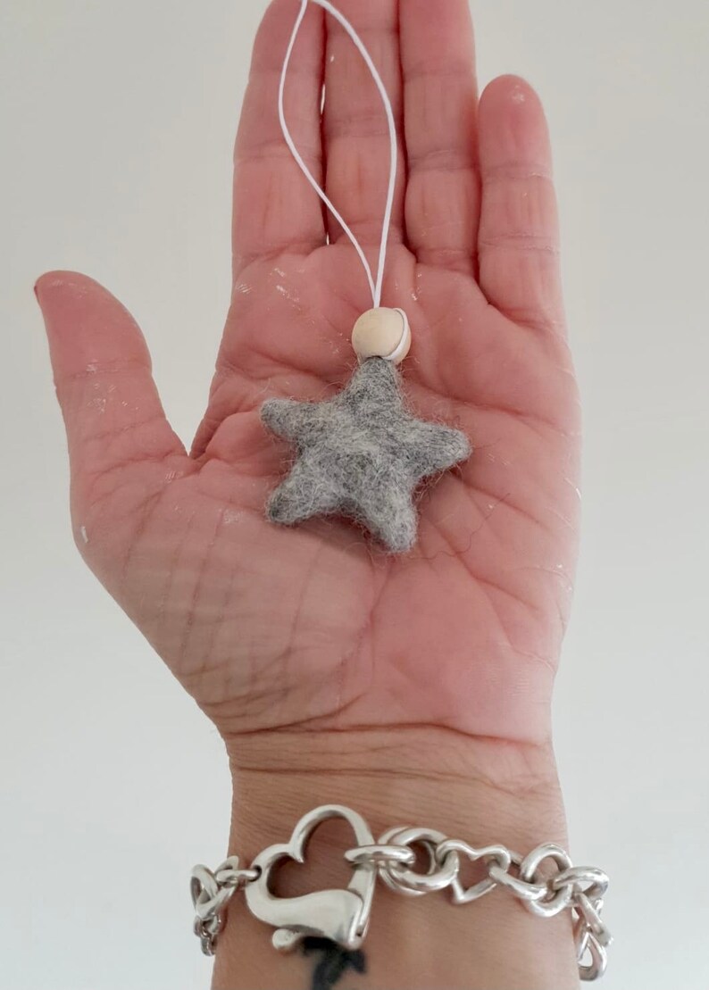 May include: A gray felt star ornament with a wooden bead and white string for hanging.