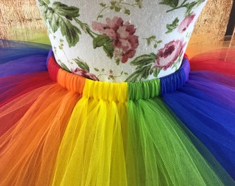 May include: A rainbow tulle skirt with a gathered elastic waistband. The skirt is made of multiple layers of tulle in the colors of the rainbow, from red to purple.