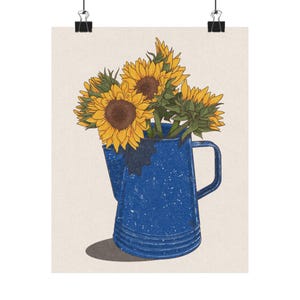 May include: A print featuring a blue enamelware pitcher filled with sunflowers. The sunflowers have yellow petals and brown centers. The pitcher has a handle and is speckled with white. The background is a light beige color.