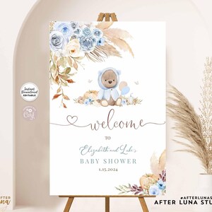 May include: Welcome sign for a baby shower with a blue and brown teddy bear illustration, floral and fall-themed decorations, and the text "Welcome to Elizabeth and Luke's Baby Shower 1.15.2024".