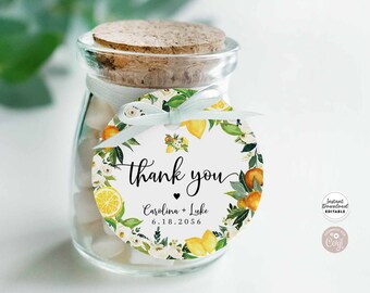 Puede incluir: Una etiqueta redonda blanca de agradecimiento con un diseño de limón y flores. La etiqueta dice "gracias" con un corazón y "Carolina + Luke 6.18.2056".