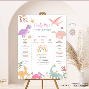 May include: A printable first birthday sign featuring a dinosaur theme. The sign includes the name "Emily Rose", a profile section with measurements, and a list of favorites. The sign is displayed on a wooden easel.