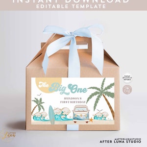 Könnte beinhalten: Eine braune Geschenkbox mit einem blauen Band und einem Etikett, auf dem "The Big One" mit einer Strandszene und einem Vintage-Van steht. Das Etikett sagt auch "Hundson's First Birthday".