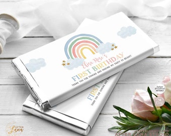 Könnte beinhalten: Zwei Schokoladenriegelverpackungen mit einem Regenbogen-, Wolken- und Sternen-Design. Die Verpackungen tragen den Text "Elisa Rose's First Birthday" und "Thank you for coming and making my party so bright!". Die Verpackungen sind silberfarben.