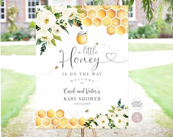 May include: A white printable sign with a honey pot and honeycomb design. The text reads "a little Honey is on the way, welcome to Carol and Victor's Baby Shower 10.15.20XX".