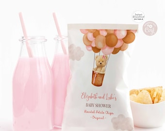 May include: A white chip bag with a pink and brown balloon design. A teddy bear is in a basket with a pink bow. The text on the bag reads "Elizabeth and Luke's Baby Shower Roasted Potato Chips - Original - "