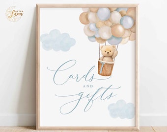 May include: A printable sign with a blue and brown teddy bear in a hot air balloon with blue and beige balloons. The sign says "Cards and Gifts" in blue cursive writing.