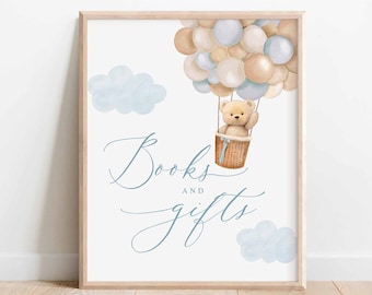 May include: A watercolor illustration of a teddy bear in a hot air balloon made of balloons. The balloon is floating above clouds. The text "Books and Gifts" is written in cursive below the balloon.