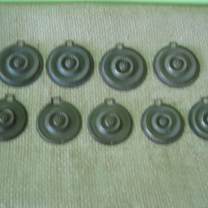 May include: Ten round, silver-colored metal discs with a raised center and concentric circles.