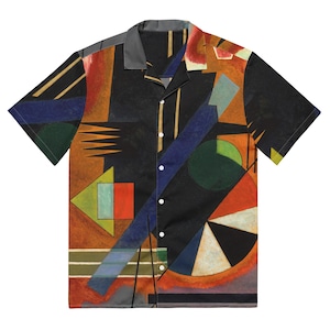 Puede incluir: Una camisa de manga corta con botones y un patrón geométrico en tonos de rojo, naranja, amarillo, verde, azul y negro. La camisa tiene cuello y cierre de botones.