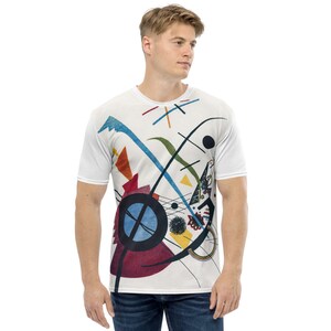 May include: A white t-shirt featuring a colourful abstract design with geometric shapes, lines, and a large blue circle. The design is reminiscent of the work of artist Wassily Kandinsky.