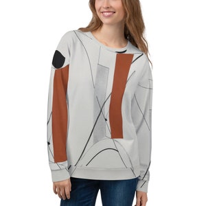 May include: A light grey sweatshirt with a geometric design featuring black, white and rust-coloured lines and shapes.
