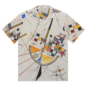 Peut inclure: Une chemise à manches courtes à boutons avec un imprimé géométrique abstrait dans des tons de jaune, bleu, rouge, noir et blanc. La chemise a un col et une fermeture à boutons.