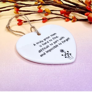 May include: White heart-shaped ceramic ornament with a jute string for hanging. The ornament features black text that reads, "A truly great team is hard to find, difficult to part with and impossible to forget!" Decorative floral design.