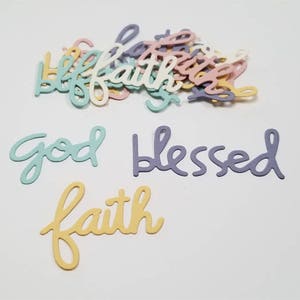 Puede incluir: Surtido de recortes de papel de color pastel con las palabras "Dios", "Bendito" y "Fe" en una fuente cursiva.