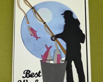 May include: A handmade greeting card featuring a silhouette of a fisherman with a fishing rod, a bucket with fish, and the words "Best Wishes." The background includes a blue circle with a white moon and two pink fish.