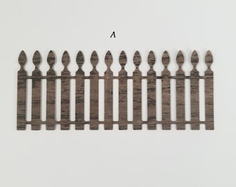 May include: A decorative wooden fence with a weathered brown finish. The fence has vertical slats and pointed tops, with the letter "A" above it. This item is suitable for crafts and miniature projects.