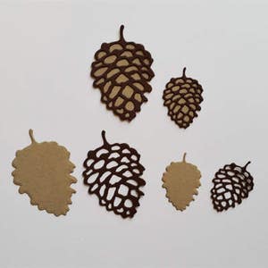 May include: Six brown paper pine cone cutouts of varying sizes. The pine cones are intricately cut with a delicate design.