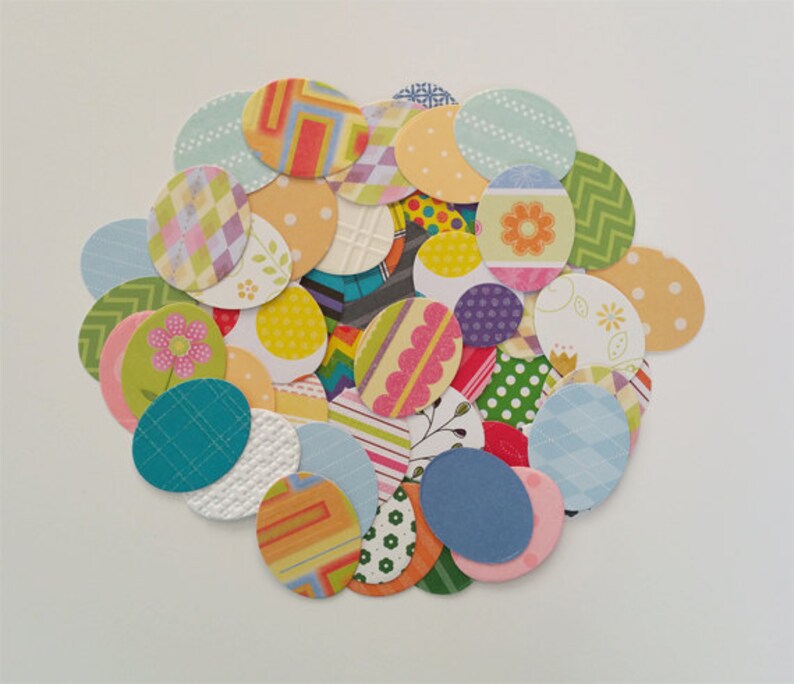 May include: A collection of colorful paper circles with various patterns, including polka dots, stripes, and floral designs. The circles are arranged in a circular pattern, resembling a bouquet of flowers.