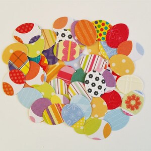 May include: A collection of colorful paper circles with various patterns, including polka dots, stripes, and floral designs. The circles are arranged in a loose, overlapping pattern, creating a visually appealing and festive display.