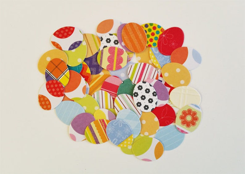May include: A collection of colorful paper circles with various patterns, including polka dots, stripes, and floral designs. The circles are arranged in a loose, overlapping pattern, creating a visually appealing and festive display.