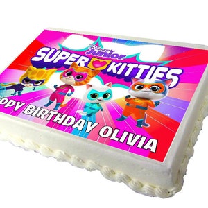 May include: A white cake with a pink, purple and yellow icing design. The cake is decorated with a printed image of four cartoon cats wearing superhero costumes. The image includes the text "Super Kitties" and "Happy Birthday Olivia".