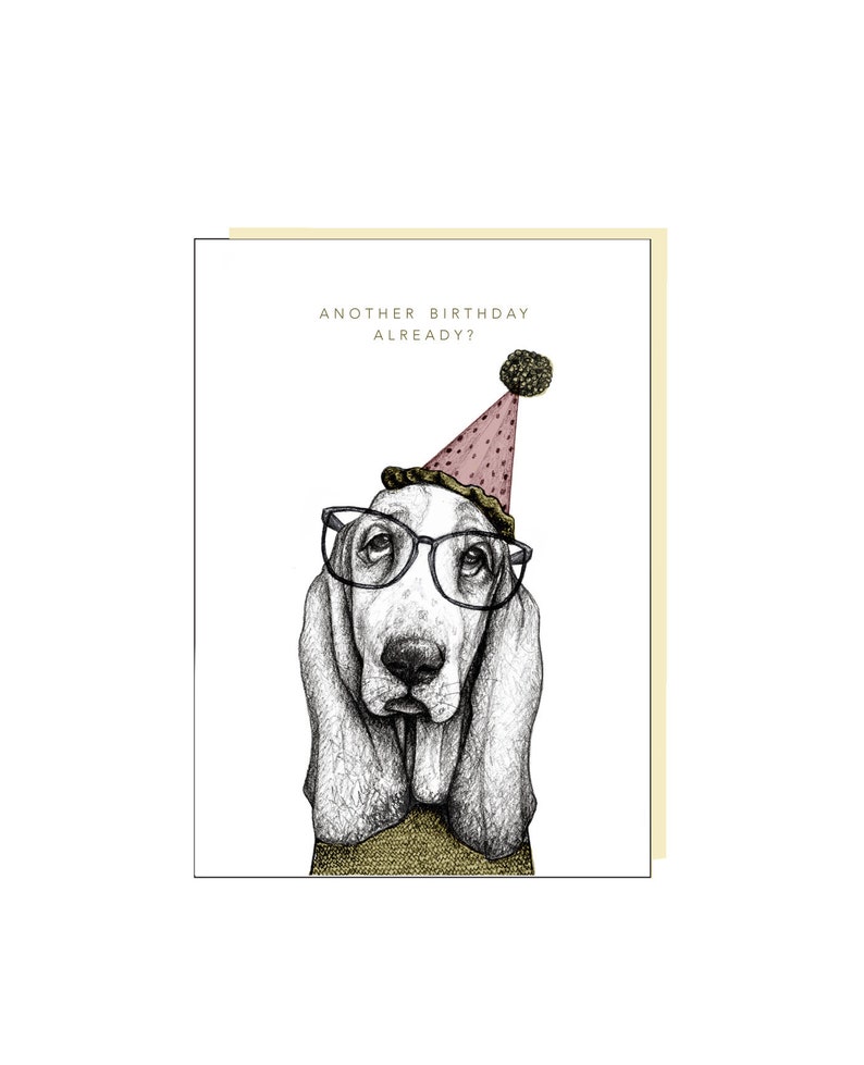 May include: A birthday card featuring a black and white illustration of a basset hound wearing glasses and a pink party hat. The text on the card reads "Another birthday already?"