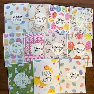 May include: Ten handmade Easter cards with different patterns and designs. Each card features a circle with the text "Happy Easter" in black lettering.