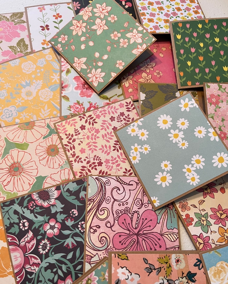 May include: Assortment of patterned paper cards with floral designs in various colors, including pink, green, blue, and yellow. The cards have brown borders and are arranged in a random pattern.