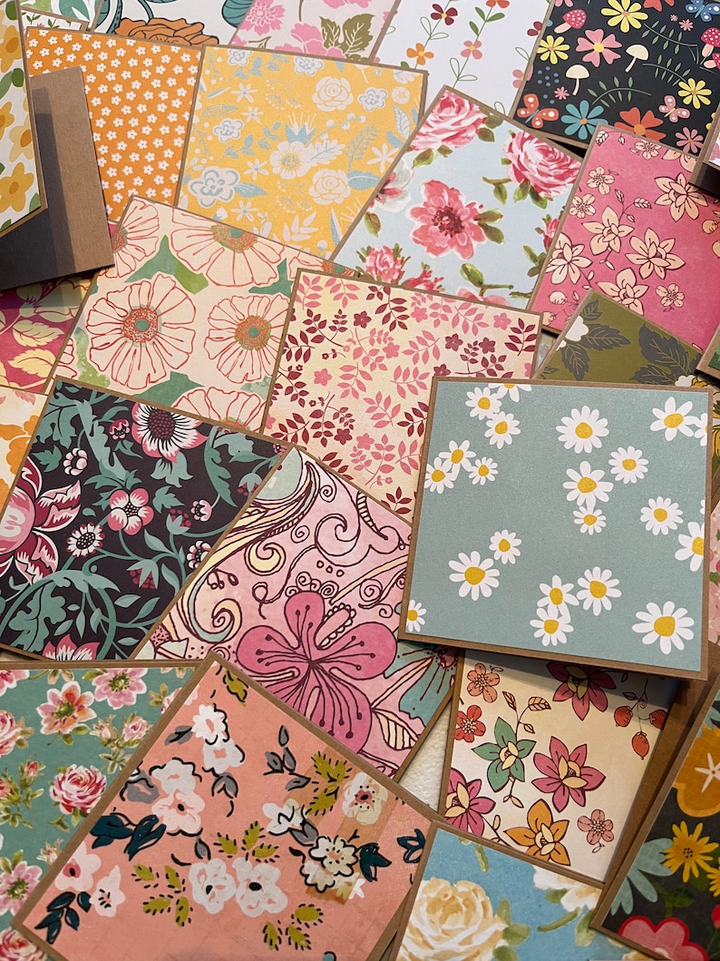 May include: A collection of patterned paper cards with brown borders. The cards feature various floral designs in shades of pink, blue, green, and yellow.