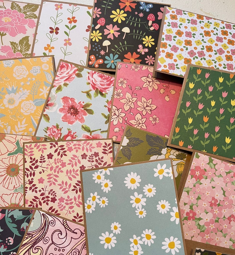May include: A collection of 12 different patterned paper cards with floral designs. The cards are all square and have a brown border. The patterns include daisies, tulips, butterflies, and other floral motifs.