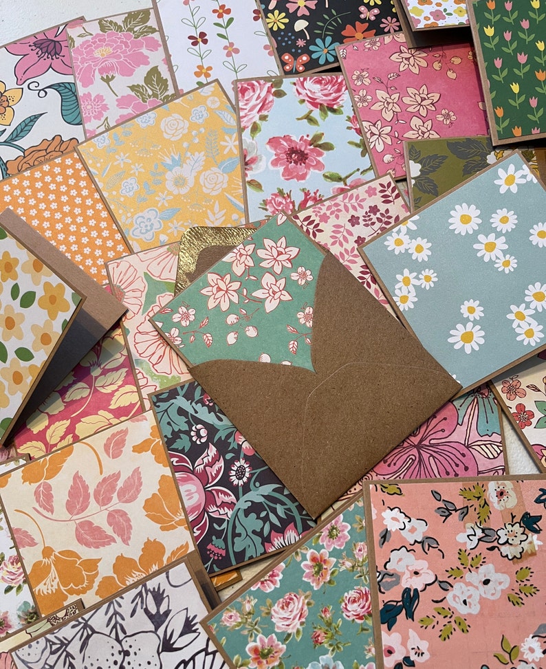 May include: A collection of small, square cards with various floral patterns. The cards are arranged in a random pattern and some are partially overlapping. The cards are all brown on the edges and have a rustic, vintage aesthetic.
