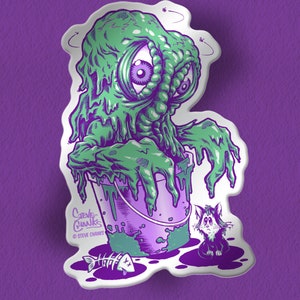 May include: A green, gooey monster with one large eye is trapped in a purple bucket. A small, black and white cat with a sad expression watches from the side. The text "Steve Chanks" and "@STEVE CHANKS" is at the bottom of the image.