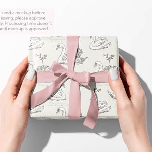 May include: A wrapped gift box with a swan pattern, tied with a pink ribbon and bow. The box is held by hands against a white background. Text on the image reads: "I will send a mockup before processing, please approve promptly. Processing time doesn't start until mockup is approved."