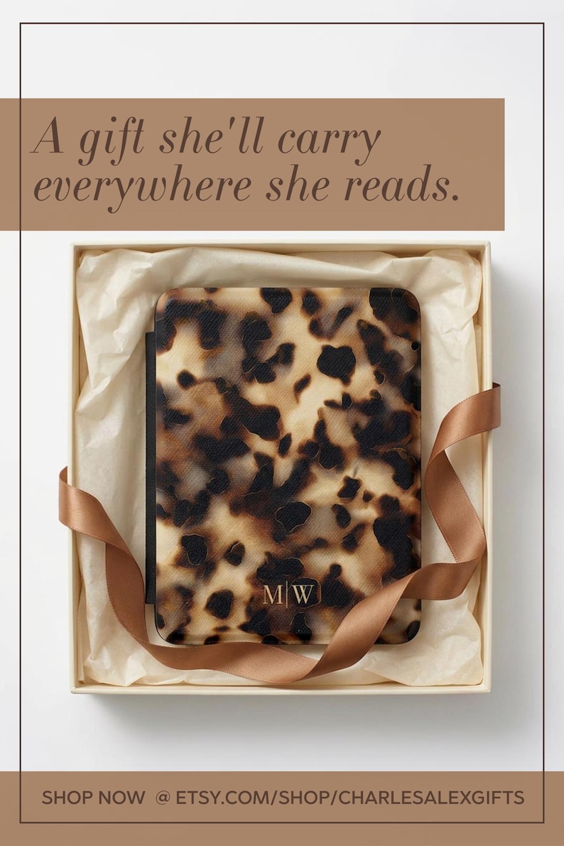 May include: A rectangular e-reader case featuring a brown and black tortoiseshell pattern with the gold-coloured initials M|W centred at the bottom. The case is presented inside a square box lined with cream-coloured tissue paper and a brown ribbon.