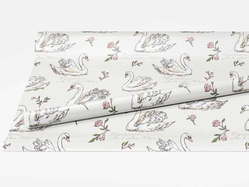 Roll of swan wrapping paper spread open on a white background showing full pattern repeat with ivory backdrop blush flowers and personalized wedding text option