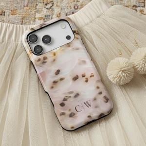 May include: A white ceramic mug with a black handle and the text "But First, Coffee" in a bold, black font. The mug is set against a blurred background, suggesting a cozy setting.