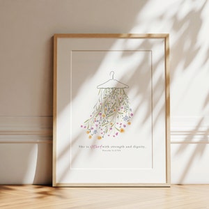 May include: A framed print featuring a floral design and the text "She is clothed with strength and dignity. Proverbs 31:25 NIV".