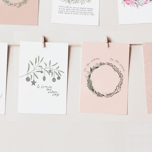 May include: Five Christmas cards with pink backgrounds and various illustrations. The cards feature a stack of presents, a branch with ornaments, a wreath, a dove with an olive branch, and a text-based card that reads "Peace on Earth".